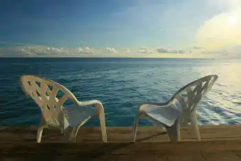 Admirez le lever du soleil sur la mer depuis cet endroit paisible. Chaises de détente sur la terrasse ensoleillée d'une longhouse sur l'île de Mabul, offrant un coin tranquille pour admirer le lever du soleil sur la mer de Célèbes.