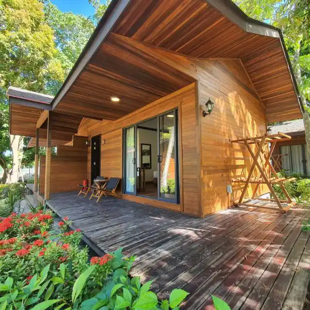 Modern luxury beach chalet at Borneo Divers Mabul Resort, featuring a spacious wooden deck surrounded by lush tropical gardens.