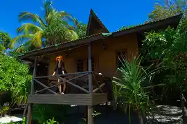 Guest relaxing on the private veranda of a beach chalet, nestled amongst the lush, tropical jungle of Lankayan Island.