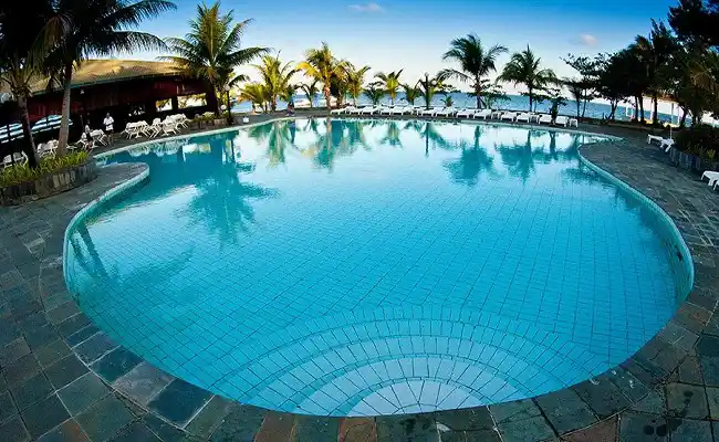 Inviting resort swimming pool at Layang Layang, surrounded by palm trees and offering a perfect place for divers to relax after exploring the deep walls.