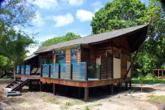 Modern wooden beach chalet at Mataking Island Resort, with a spacious deck nestled amongst lush tropical foliage for a private 5-star stay.