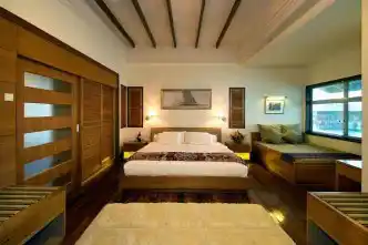 Luxurious over-the-water bedroom in the Borneo Villa at Mabul Water Bungalows, with elegant furnishings and direct access to a private sea-view balcony.