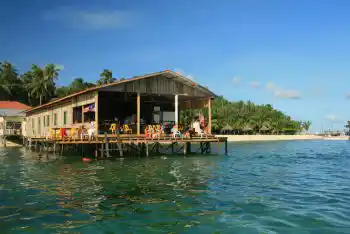 Partagez vos anecdotes et profitez de la vue avec les autres voyageurs. Des clients se détendent sur la terrasse commune de la longhouse Mabul Backpackers, un hébergement sur pilotis économique pour plongeurs et voyageurs.