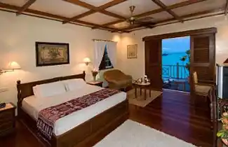 Luxurious duplex room at Mabul Water Bungalows, featuring elegant wooden furniture and a private balcony with a breathtaking view of the turquoise ocean.
