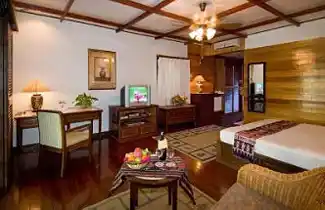 Warm and inviting luxury room at Mabul Water Bungalows, featuring a welcome fruit basket and comfortable amenities for a perfect holiday.