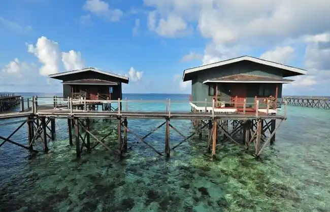 Luxurious overwater villas at Pom Pom Island Resort, connected by a jetty over the crystal-clear turquoise reef, perfect for a 5-star honeymoon.
