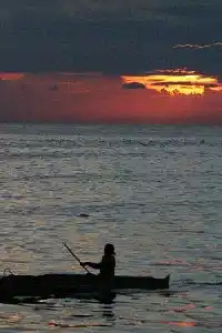 Découvrez la beauté tranquille d'un coucher de soleil à Mabul. Silhouette d'un batelier solitaire se découpant sur un coucher de soleil flamboyant au-dessus de la mer à Mabul, pour clore une journée de plongée.