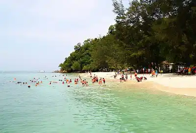 This island is a popular and accessible day trip. Visitors enjoying the beautiful white sand beach and clear turquoise water at Pulau Mamutik, a popular island for day trips and snorkeling in Kota Kinabalu.