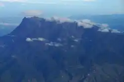 Majestic massif of Mount Kinabalu, Southeast Asia's highest peak, with its rugged granite summit partially shrouded in clouds.