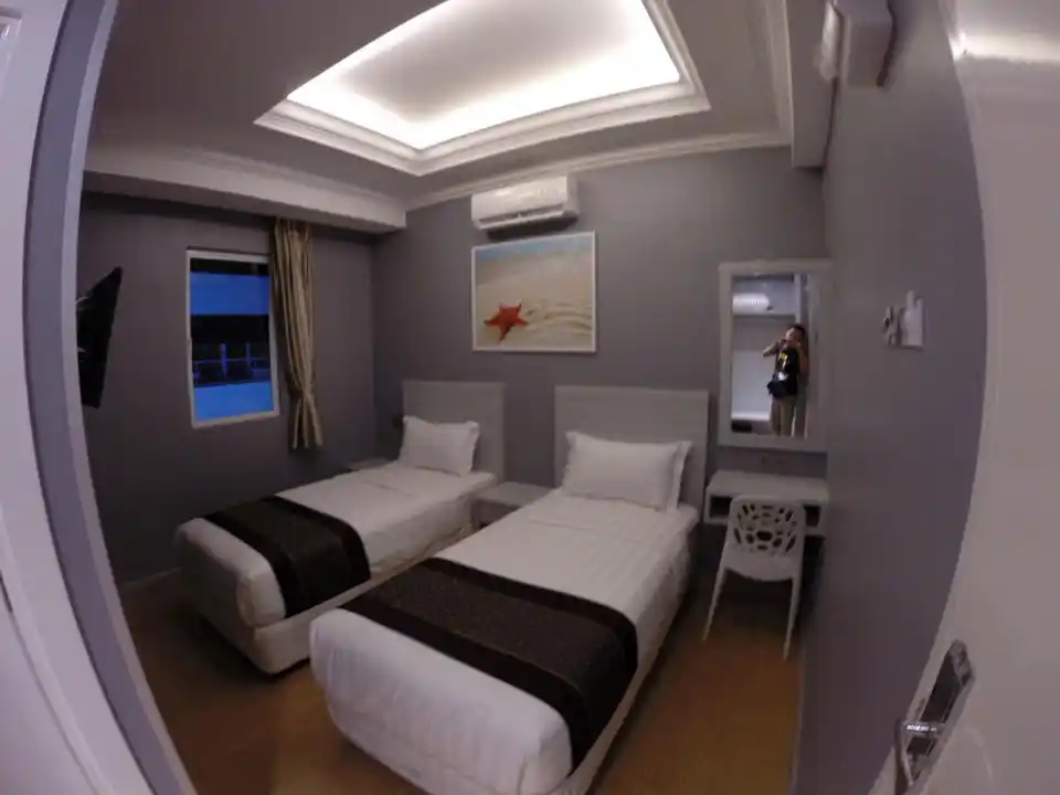 Chambre Standard Twin moderne et confortable à l'Ocean Inn 3 de Semporna, avec deux lits simples et un éclairage encastré élégant.