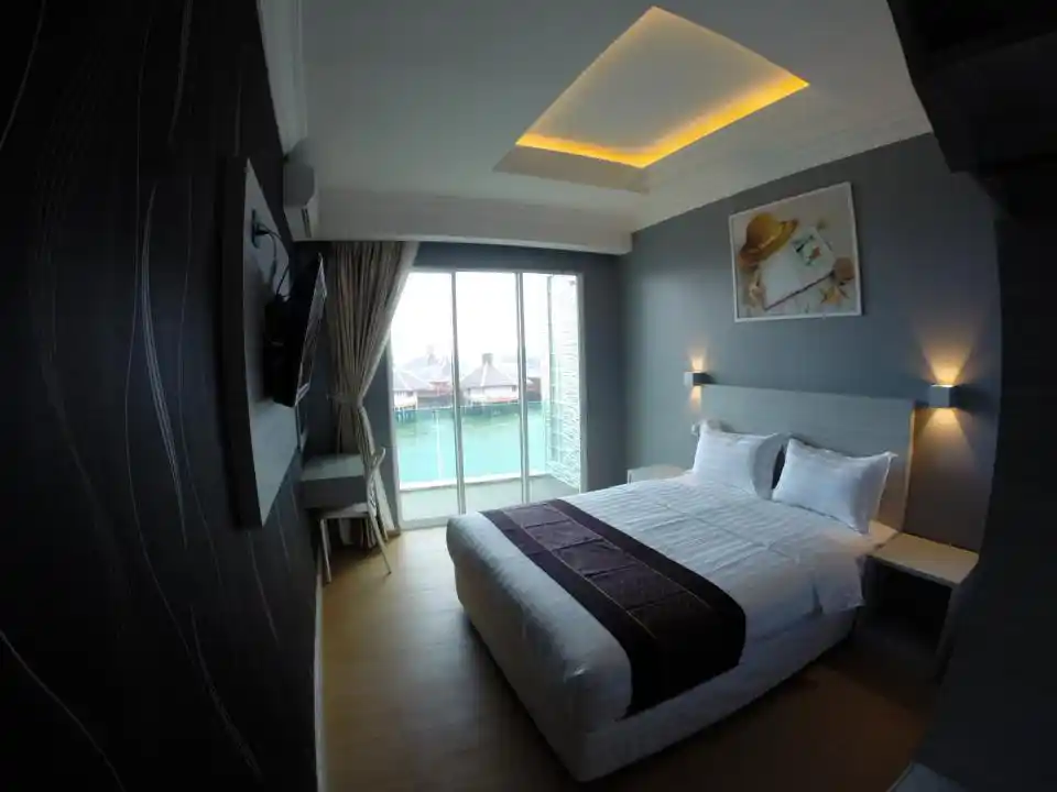 Intérieur moderne et propre d'une chambre à l'Ocean Inn 3 de Semporna, avec un lit double confortable et un balcon donnant sur la mer.