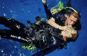 Scuba diver practicing in-water rescue breathing techniques on a simulated victim during a PADI Rescue Diver course in Mabul.