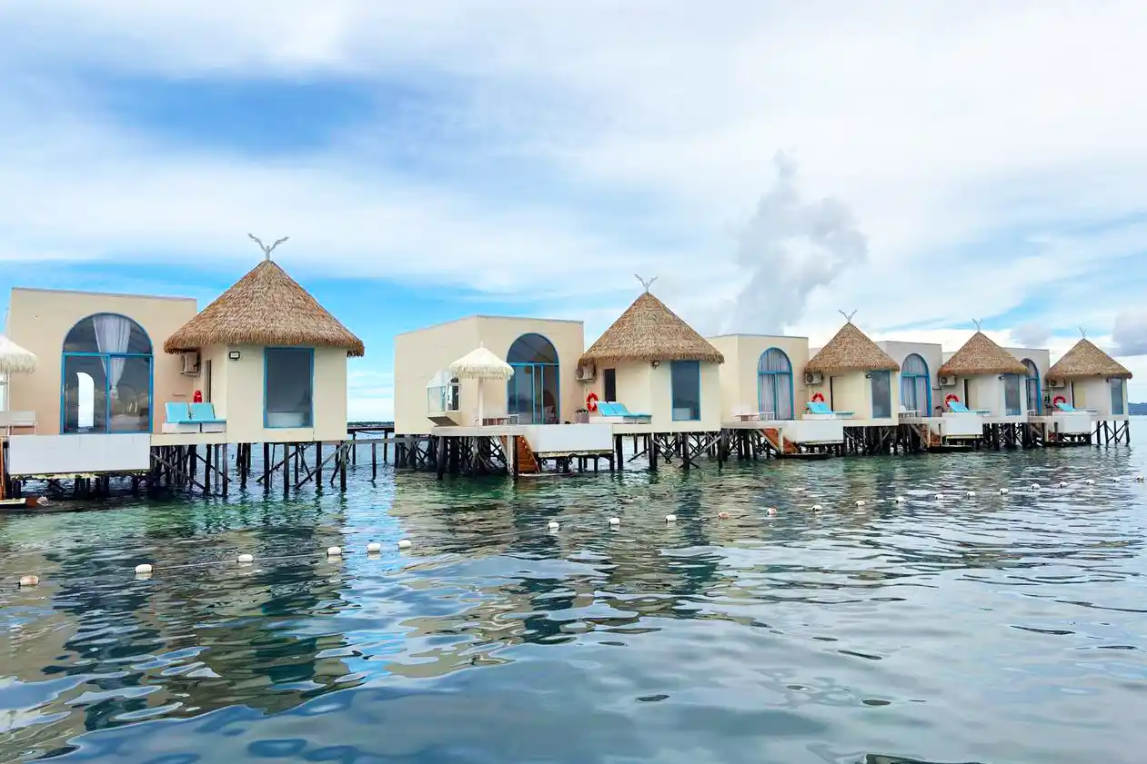 Unique and modern overwater villas at Royal Resort Semporna, featuring a distinctive design with thatched roofs and arched windows over the sea.