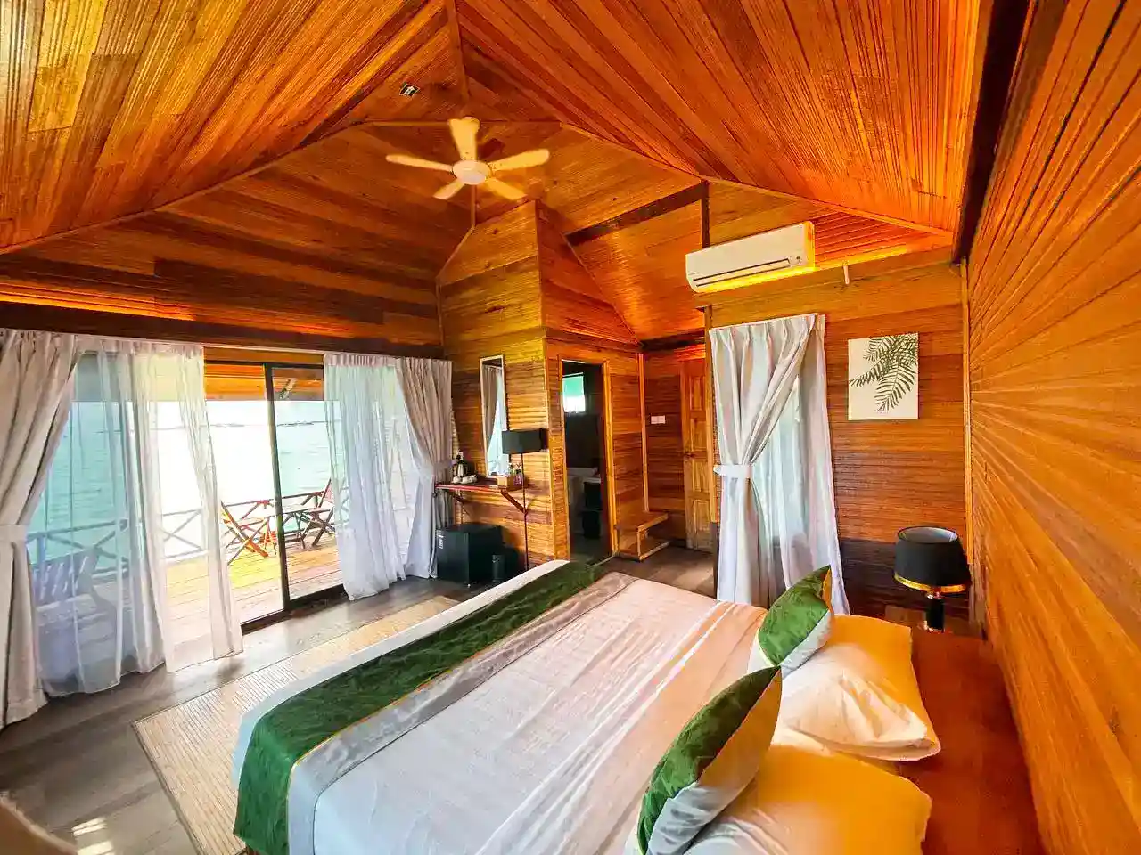 Warm and inviting overwater chalet at Sky Water Villas, featuring beautiful wood-paneled walls and a private balcony with stunning sea views.