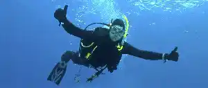 The universal sign for everything is okay underwater. Smiling scuba diver flashes twin thumbs-up while hovering mid-water at Sipadan capturing the exhilaration of exploring world-class reefs.
