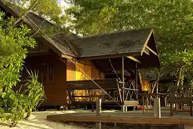 Relax in privacy, surrounded by the island's jungle. Guest relaxing on the private veranda of a beach chalet, nestled amongst the lush, tropical jungle of Lankayan Island.
